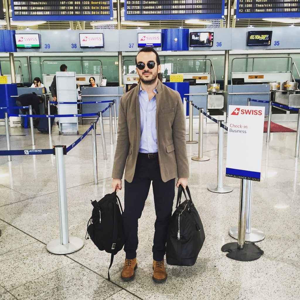 Sport jacket by Alexander McQueen, shirt by Brooks Brothers, trousers by COS, sunglasses by Ray-Ban, belt by John Varvatos, suede working boots by Brunello Cucinelli, weekend bag by Jil Sander, backpack by Prada.
