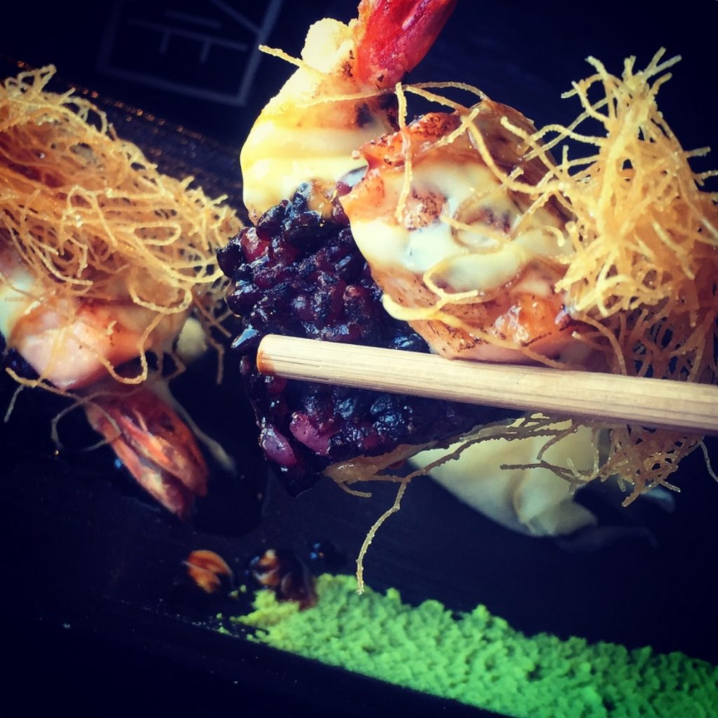 Signature RAKKAN ROLL: black rice, avocado, shrimp tempura, spicy sauce, seared salmon in togarashi butter, wasabi mayo, kantaifi
